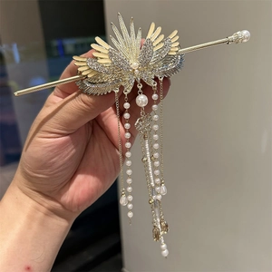 Detail of a golden wing hair clip with rhinestones, pearls and beaded tassels