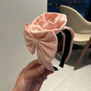 Pink fabric headband featuring a blooming rose and bow design for a stylish feminine look
