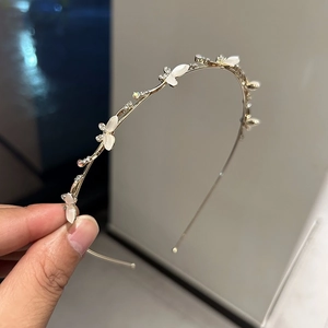 Détail d'un serre-tête doré élégant orné de pétales blancs et de petits strass colorés