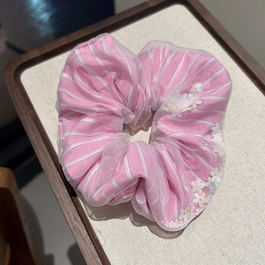 Close-up of pink striped fabric scrunchie with sheer mesh and floral sequin details