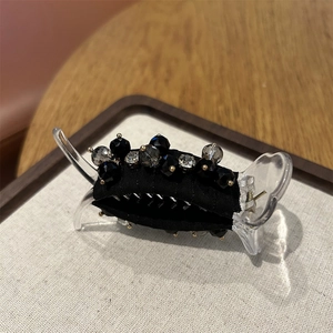 Close-up of black fabric hair claw clip with multifaceted grey and clear crystal beads