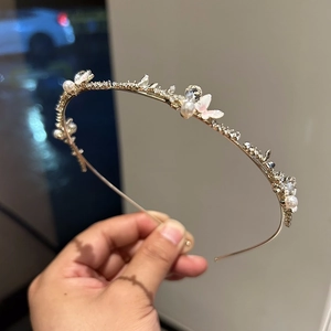 Détail du serre-tête doré avec papillons en émail rose, perles et cristaux fins