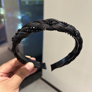 Detailed close-up of a black braided headband featuring sparkling crystal beads and inner teeth