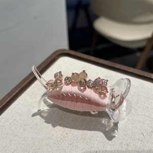 Detailed close-up of pink fabric hair claw with shimmering crystal beads decoration