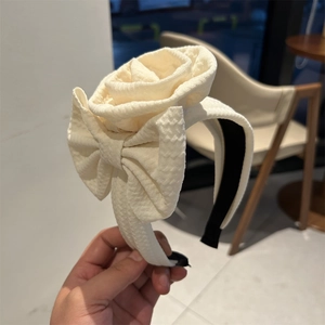 Detail of cream floral headband with textured rose flower and elegant bow design