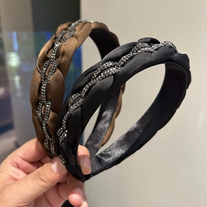 Detail eines geflochtenen Stirnbandes mit silbernem Strassbesatz in Schwarz und Braun