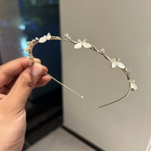 Gros plan d'un serre-tête doré orné de papillons en opale blanche et de cristaux brillants