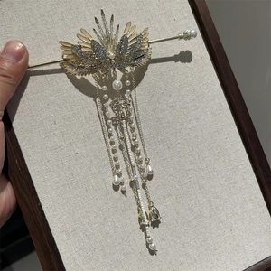 Detailed close-up of a golden wing hairpin with pearls and tassels for retro styling