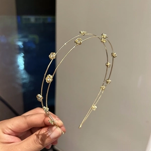 Detailed close-up of double-layered gold floral headband with sparkling rhinestones