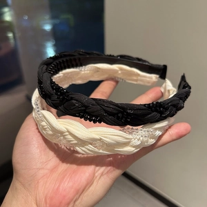 Detail of woven fabric headbands with elegant beaded texture and braided design in cream and black