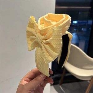Close-up of a yellow honeycomb textured fabric headband with a large decorative bow