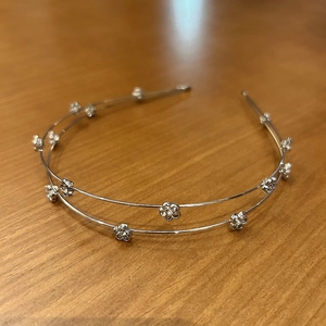Detail of silver double-layered headband with small rhinestone flower decorations
