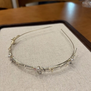 Détail d'un serre-tête doré avec perles blanches, pétales roses et strass brillants