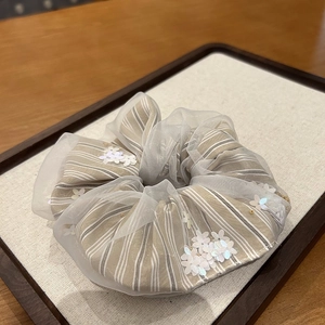 Detailed macro view of tulle floral scrunchie with sequins and striped fabric texture