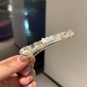 Detailed close-up of champagne gold hair clip with crystals, pearls and rhinestones