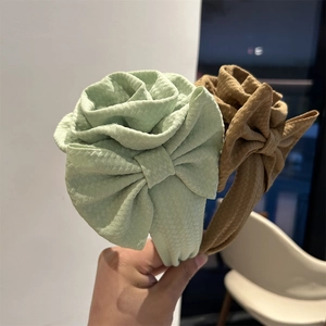 Detailed view of oversized fabric floral headbands in mint green and khaki colors