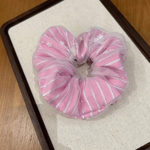 Close-up of pink striped scrunchie with sheer mesh layer and white floral embellishments