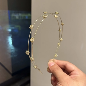 Detail of double-layered gold headband featuring delicate floral accents and rhinestones