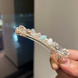 Detailed macro view of crystal duckbill hair clip with pearls and gemstones