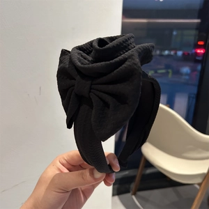 Detail of elegant black floral headband with large 3D fabric rose and bow accent