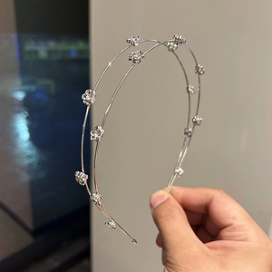 Detail of silver double-layered headband featuring small rhinestone flower charms
