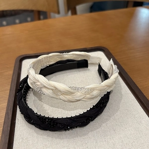 Detail of braided satin headbands in cream and black with delicate bead embellishments