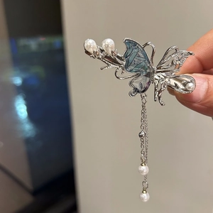 Dettaglio del fermaglio per capelli a farfalla in metallo con nappe di perle blu