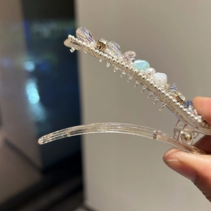 Detail of handmade hair clip featuring crystal beads and faux pearls on a transparent base