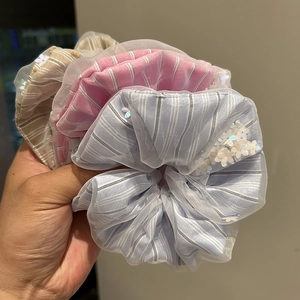 Close-up of three striped tulle scrunchies with white floral sequins in pastel colors
