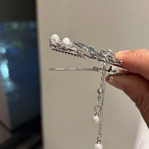 Dettaglio laterale di un fermaglio per capelli a farfalla argento con perle e nappe