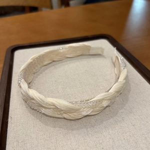 Detailed macro view of woven cream satin headband with elegant crystal bead accents