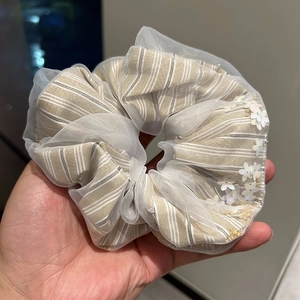 Detail of layered tulle scrunchie with white flower sequins and striped fabric texture