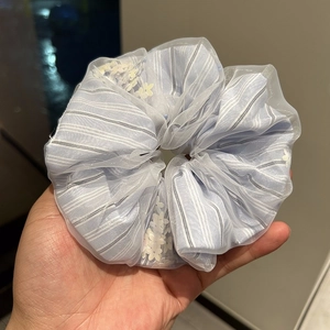 Close-up of light blue striped scrunchie with floral embroidery and white tulle overlay