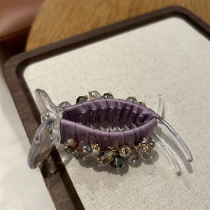 Detailed view of luxury purple satin hair claw clip decorated with faceted crystal beads