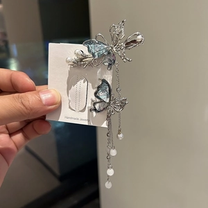 Fermaglio per capelli a farfalla argento con motivi blu, perle e nappe lunghe su carta