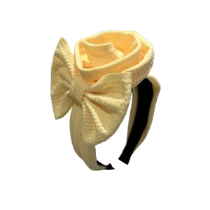Elegant pale yellow flower headband featuring a stylish bow and textured fabric rose design