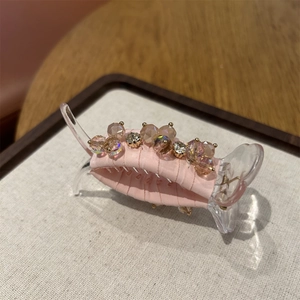 Close-up of pink fabric hair claw clip with crystal bead embellishments and metal accents