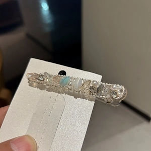 Close-up of handmade hairpin with sparkling crystals, blue gems and faux pearls