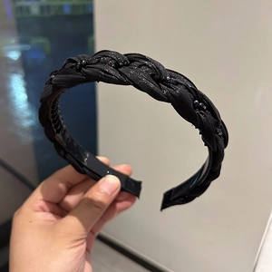 Detail of a braided black headband with sparkling crystal beads held by hand
