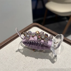 Detail of crystal beads and purple satin fabric on a large hair claw clip for women