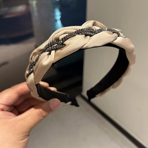 Makroaufnahme des geflochtenen Stirnbands mit Champagner-Satin und dunklen Strassketten