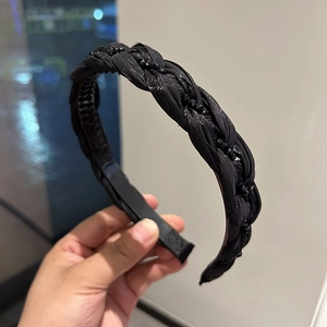 Close-up of a black braided headband with beaded accents and non-slip interior teeth