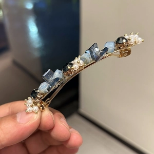 Detail of crystal duckbill hair clip with blue rhinestones and white pearls for women