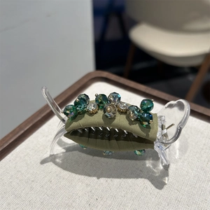 Detailed close-up of a dark green crystal hair claw with handcrafted beadwork