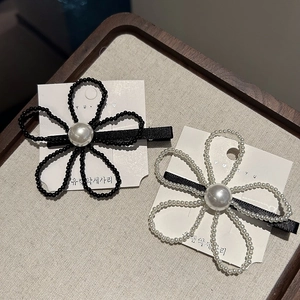Détail de barrettes fleurs en perles noires et blanches sur une carte de présentation