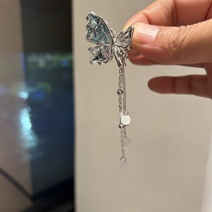 Dettaglio del fermaglio per capelli a farfalla argentata con ali blu e nappe di perle