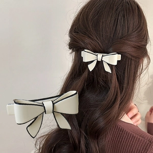 Detail view of acetate bow hair clip with black border on dark brown hair