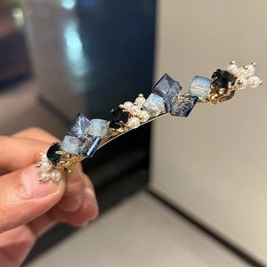 Detailed macro view of blue crystals and white pearls on the elegant gold hair clip