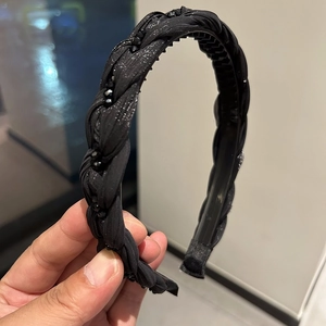 Detail view of black braided headband with shiny beads and inner non-slip teeth for secure grip