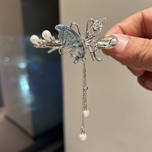 Dettaglio del fermaglio a farfalla argento con ali blu e nappe di perle eleganti